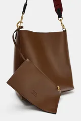 Bolso de hombro tipo saca en color marrón, con diseño minimalista y cierre de clip metálico. Incluye una correa de hombro con detalles troquelados en contraste y herrajes dorados.