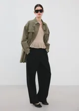 Cardigan de punto fino color beige, entallado, con cuello en V, manga larga acampanada, bajo con volante y cierre frontal con botones.