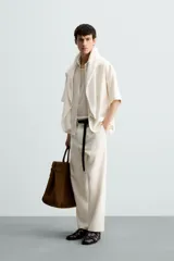 Pantalón de calce relajado confeccionado en tejido de viscosa y yute color tostado. Presenta cintura elástica ajustable con cordón, bolsillos laterales, bolsillos traseros de vivo y cierre frontal con cremallera y botón.