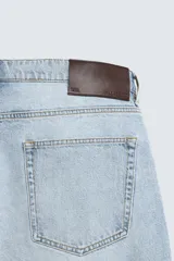Pantalón de jean color celeste con efecto lavado, de corte recto y tiro medio, con diseño de cinco bolsillos y cierre frontal con botones.