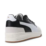 Championes urbanos Puma modelo Shuffle Downtown, con diseño retro inspirado en el básquet. Presentan una combinación de cuero sintético negro en el panel lateral y puntera de gamuza en tono gris claro. Incluyen la icónica franja lateral de Puma en blanco, suela de goma color caramelo y plantilla SoftFoam+ para mayor comodidad.