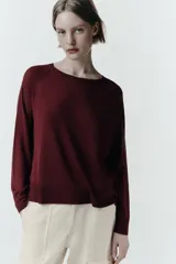 Jersey de punto negro con cuello redondo, manga larga y aberturas laterales en el bajo. Acabados en rib.