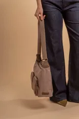 Bandolera de tafeta impermeable color beige, con dos bolsillos frontales con cierre y correa regulable. Diseño práctico y liviano ideal para uso diario.