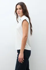 Remera de cuello polo en color crudo, con mangas cortas y detalle de bordado en contraste a lo largo del escote y en los bordes de las mangas.