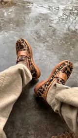 Mocasines de cuero con estampa animal print de leopardo, detalle artesanal trenzado en el frente, franja de cuero liso en el empeine y suela plana.