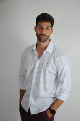 Camisa de manga larga con estampado de rayas verticales en color celeste y blanco, cuello clásico y cierre frontal con botones. Presenta un pequeño logo bordado en el pecho.