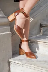 Zapatos de cuero color marrón con taco cuadrado de 6 cm, punta fina y tira al tobillo con hebilla metálica.