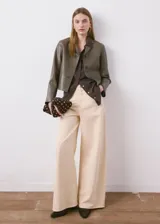 Chaqueta corta de poliuretano con acabado símil cuero, color verde militar, con cuello camisero, bolsillos frontales con solapa y cierre de botones.