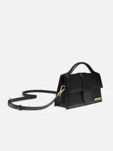 Bolso estructurado Jacquemus modelo Le Grand Bambino de cuero liso color negro, con asa superior, solapa frontal con cierre magnético, correa larga extraíble y logotipo metálico dorado.