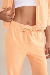 Pantalón jogger color durazno de tejido frosty con superficie plush de tacto suave y aterciopelado. Tiene cintura media con ajuste mediante amarre y bolsillos laterales.