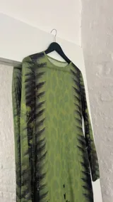 Vestido midi ajustado de microtul verde con estampado abstracto en tonos oscuros. De mangas largas y cuello redondo, es una prenda transparente y elástica.