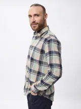 Camisa de manga larga confeccionada en tela de franela con estampado de cuadros en tonos beige, verde y azul marino. Presenta cuello clásico, cierre frontal con botones y un bolsillo en el pecho.