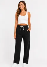 Pantalón de felpa color negro, de corte recto y holgado, con cintura elástica ajustable mediante cordón y bolsillos laterales.
