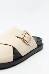 Sandalia negra con tiras cruzadas y hebilla metálica lateral.