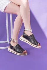 Sandalias de cuero vacuno negro con semi plataforma, diseño pintado a mano en el frente y tira al tobillo con hebilla metálica.