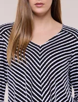 Remera de calce relajado y silueta fluida, con escote en V y mangas tres cuartos con presilla y botón. Diseño de rayas dispuestas en ángulo tipo espiga en el delantero y ruedo redondeado.