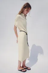 Vestido midi de punto color azul marino, de corte holgado, con cuello subido y manga corta vuelta. Incluye un cinturón fino efecto piel con hebilla metálica dorada.