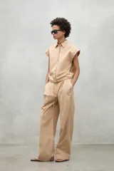 Pantalon de corte relajado y tiro alto, confeccionado en algodon, con pliegues frontales y bolsillos laterales.