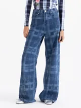 Pantalón de jean de tiro medio y pierna amplia con diseño de cuadros estampados y detalles bordados de flores en contraste. Presenta bolsillos clásicos, cierre frontal con botón metálico y recortes estructurales en las piernas.