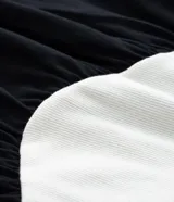 Vestido midi bicolor, con parte superior color crema y falda negra, confeccionado en tejido de punto rib de algodón. Tiene escote redondo y mangas cortas.