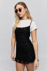 Vestido corto de encaje negro con breteles finos y corte ajustado al cuerpo.