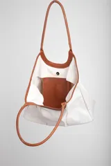 Bolso tipo tote de tela color crudo con detalles de cuero marrón en las asas y la base.