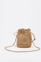 Minibolso tipo saco Bimba y Lola de diseño trenzado metalizado en color dorado, con cierre de cordón ajustable y correa fina trenzada para el hombro. Incluye parche con logo grabado en el frente.