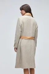 Tapado largo de lana fina con diseño de espiga en tonos beige. Presenta cuello camisero y solapas de bolsillos en cuero color suela, con cierre frontal de botones a tono.