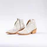 Botín de cuero vacuno color marrón oscuro, con taco de madera foliado en cuero de 5cm de altura, cierre lateral interno y horma de punta fina.