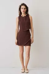 Blusa cropped color chocolate, de silueta suelta y cuello redondo, con terminación de bordes deshilachados.