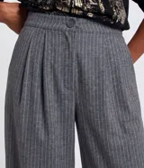 Pantalón wide leg de sastrería color gris con estampado de raya de tiza, tiro alto con cintura fija, pliegues delanteros y cierre frontal con botón y cremallera.