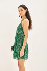 Vestido corto bretelero estampado con motivo de piel de reptil en tonos verdes, confeccionado en gasa con lurex y forrería a tono. Presenta un escote en V profundo con un aplique metálico, espalda baja con breteles cruzados regulables y elástico en la cintura.