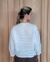 Camisa de manga larga con diseño de rayas verticales y bordados sutiles. Presenta cuello redondo, cierre frontal con botones y mangas abullonadas con volados en los hombros.