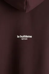 Canguro de algodón con interior cepillado, diseño boxy con hombros caídos, capucha forrada y bolsillo frontal tipo canguro. Presenta estampado con texto 'Paris' y '75008' en el frente.