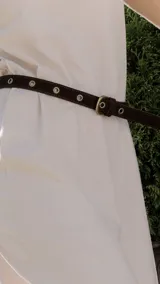 Cinto marrón de cuero con ojales metálicos y hebilla dorada.