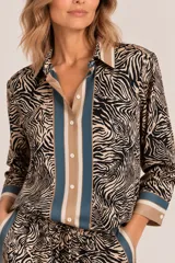 Camisa de satén con estampado animal print tipo cebra, combinada con bandas frontales y en los puños en tonos camel y azul, de manga larga y cierre frontal con botones.