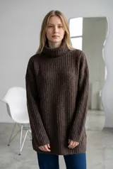 Sweater de punto gris con cuello alto, diseño acanalado y corte oversize de manga larga.