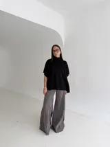 Poncho de tejido de punto color marrón chocolate, con cuello alto tipo polera y mangas cortas amplias. Presenta un diseño holgado con terminaciones acanaladas en el ruedo.