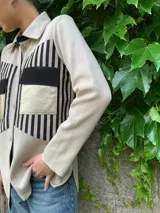 Camisa color beige con detalles de cuero negro en los bolsillos y en la parte superior del frente, de lana merino, con cuello clásico y cierre con botones.