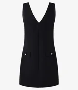 Vestido corto negro de crepé con escote en V tanto en la parte delantera como en la trasera. Tiene bolsillos delanteros con botones dorados.