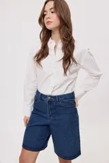 Bermuda de denim azul con calce relajado, tiro medio y largo hasta las rodillas. Cuenta con bolsillos clásicos y trabillas para cinturón.