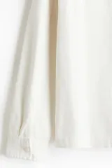 Sobrecamisa color crema de sarga de algodón, corte regular, con cuello inglés, tapeta clásica, bolsillo de parche en el pecho, mangas largas con puños abotonados y bajo recto.
