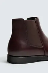 Bota estilo Chelsea de cuero negro, con elásticos laterales y suela plana a tono con ligero tacón.