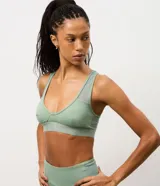 Top deportivo de microfibra color verde menta, con diseño de escote en V, banda elástica inferior ancha y detalles de tul en los breteles y laterales. Cuenta con copas estructuradas para mayor soporte.