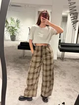 Pantalón tipo balloon de tejido plano con calce relajado, cintura elastizada y estampado cuadrillé en tonos marrones y beige.