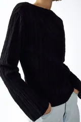 Top de manga larga en punto texturizado con escote bote y hombros levemente caídos, de color negro.