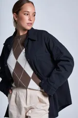 Sobrecamisa color beige de gabardina con cuello camisero, cierre frontal con botones a presión, dos bolsillos de parche en el pecho y corte holgado.