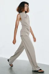 Pantalón de algodón compacto color beige, de tiro alto con cintura elástica y detalle de fajín y cordones.