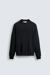 Sweater de punto negro de corte regular fit, confeccionado en algodón con cuello redondo, manga larga y acabados en rib.