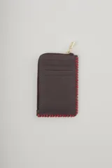 Billetera marrón de cuero sintético con cierre de cremallera y costuras rojas en los bordes.